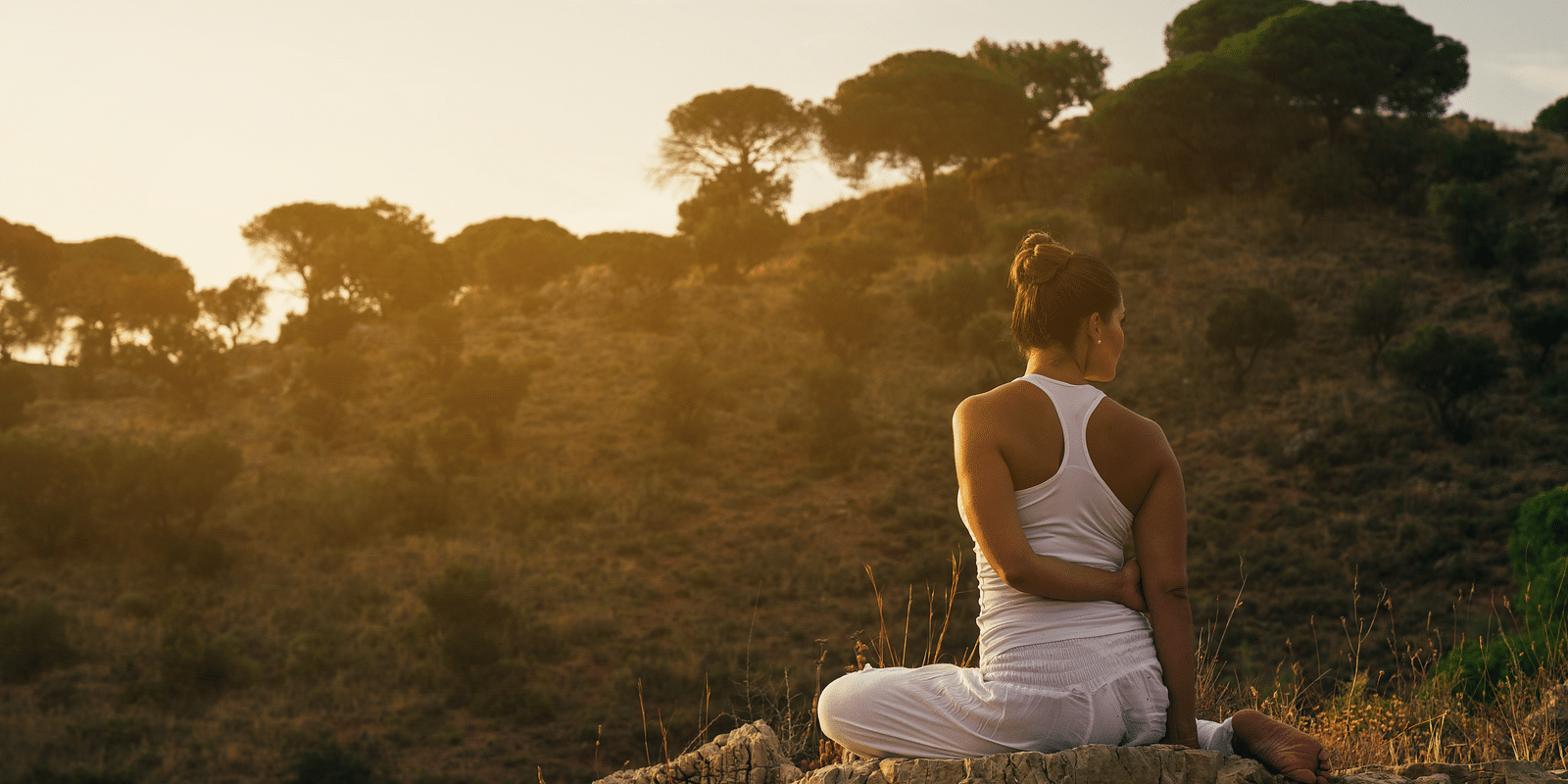 a woman doing a yoga asana while sitting outdoors